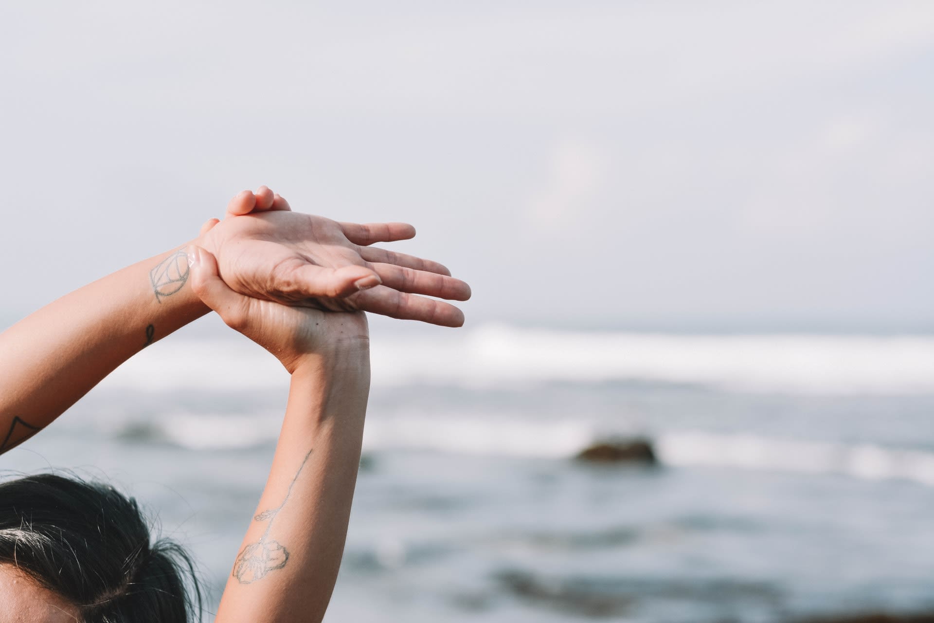 woman doing yoga side stretch on beach as part of her spiritual wellness journey